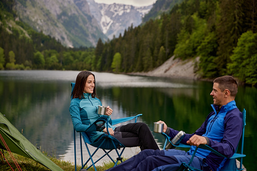 An adventurous young couple at their campsite and drinking coffee