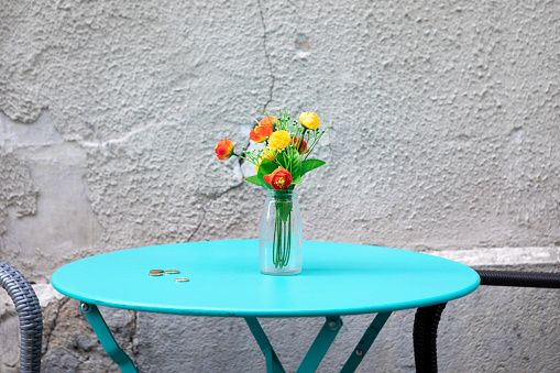 Circular turquoise cafe table by a rough wall - with coins left as a gratuity