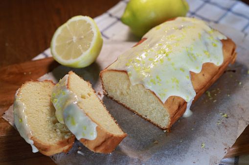Freshly baked lemon cake with lemon glaze on wooden cutting board