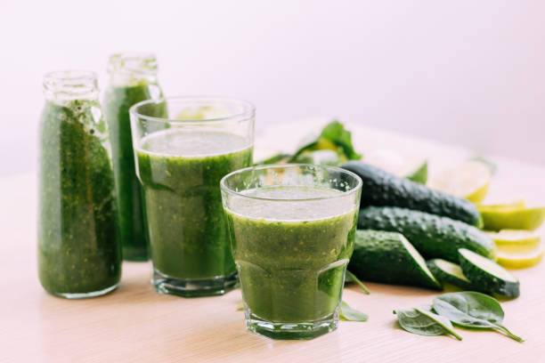 istock Green vegetable fruit smoothie in various glasses portion bottles on kitchen table, light background 1407139905