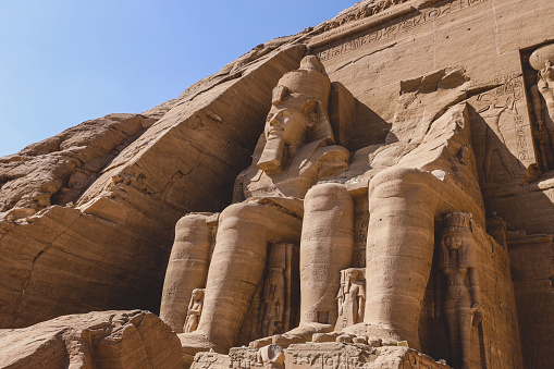 The main view of an Entrance to the Great Temple at Abu Simbel with Ancient Colossal statues of Ramesses II, seated on a throne and wearing the double crown of Upper and Lower Egypt