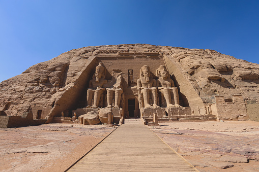 The main view of an Entrance to the Great Temple at Abu Simbel with Ancient Colossal statues of Ramesses II, seated on a throne and wearing the double crown of Upper and Lower Egypt