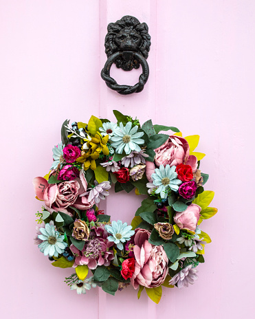 Close-up of a pretty wreath on a pink door.