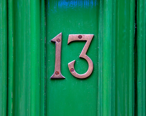 Close-up of the Number 13 on a green door.