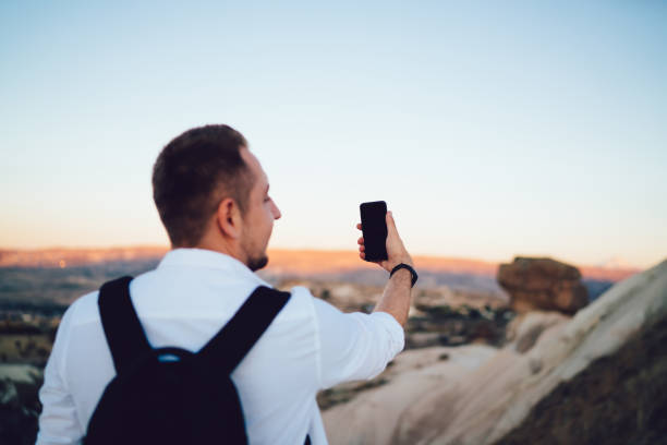 istock Man with backpack posing for taking selfie in open air 1407151811