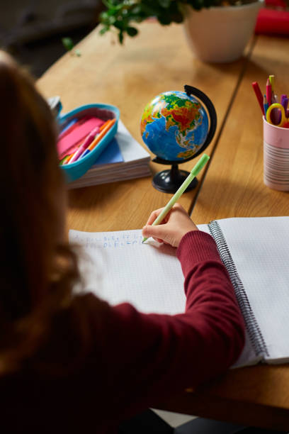 istock Focused schoolgirl sit at desk doing homework handwriting, homeschooling. 1407151966