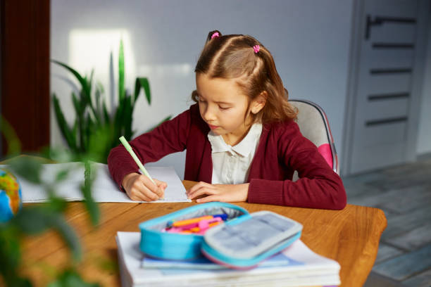 istock Focused schoolgirl sit at desk doing homework handwriting, homeschooling. 1407151972