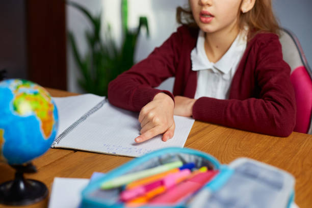 istock Schoolgirl sit at desk doing homework reading, homeschooling 1407151981