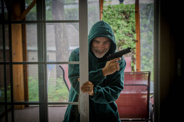 Armed man opening patio door and entering in house
