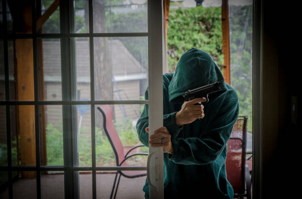 Armed man opening patio door and entering in house