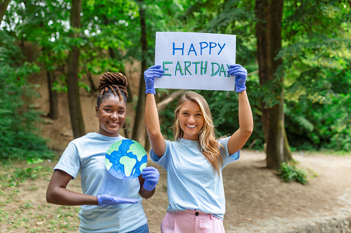 Happy Earth day! People cleaning up litter on grass. Group of international young people building team outdoor in park. Volunteer together pick up trash in the park