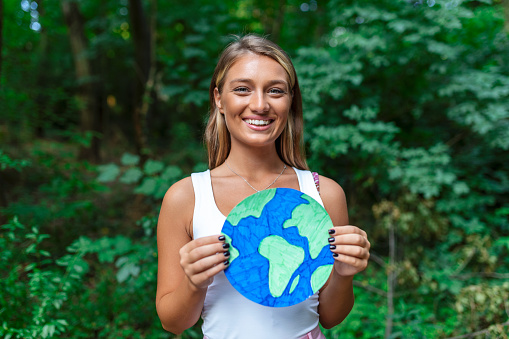 A young woman holding a planet earth and protesting against environmental pollution.