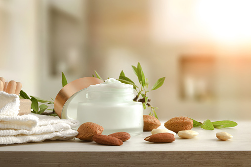Moisturizing cream with almond extract on wooden table with fruits in the bathroom. Front view. Horizontal composition.