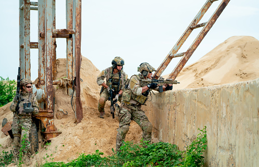 Four soldiers are climbing a wall and they are ready to fight.