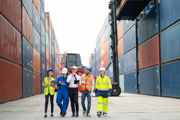 istock Group of professional engineer, worker or technician walk and discuss together about work in cargo container workplace area with crane and stack of container tank on background. 1407160449