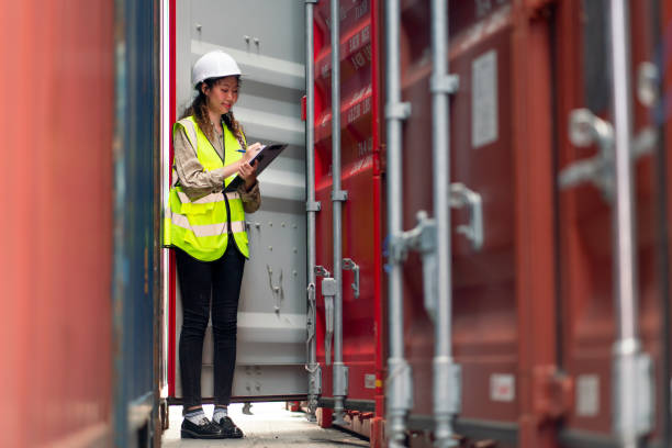 アジアの貨物コンテナ労働者の女性は、タンクのドアを開け、職場エリアで内部の製品をチェックします。 - storage tank cargo container mode of transport commercial land vehicle ストックフォトと画像