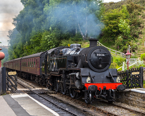 Goathland, UK - June 9th 2022: A classic steam train of the North Yorkshire Moors Railway, pulling into Goathland Railway Station in North Yorkshire, UK.