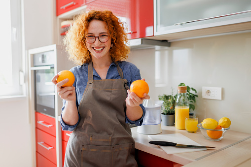 Portrait of young woman making orange juice