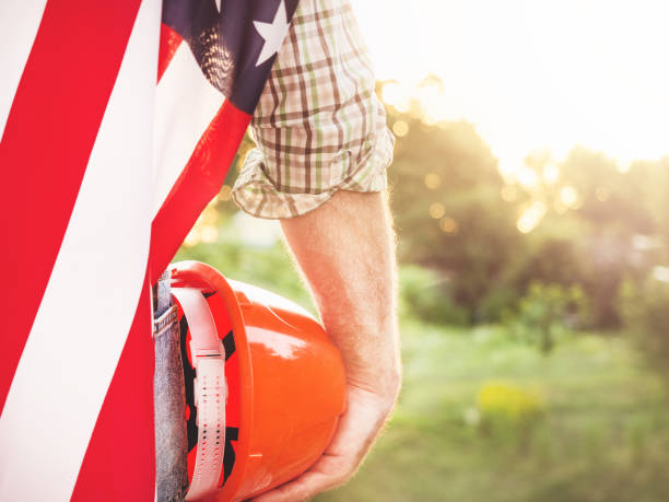istock Attractive man in work clothes, holding American Flag 1407162982