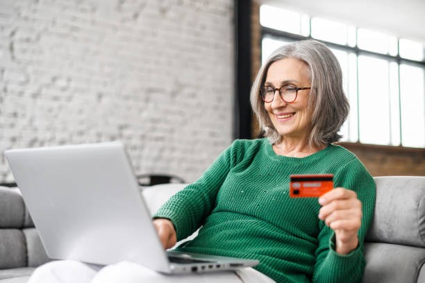 Mature businesswoman using laptop and credit card stock photo