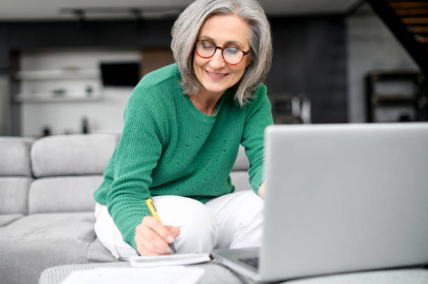 Beautiful senior woman using laptop at home stock photo