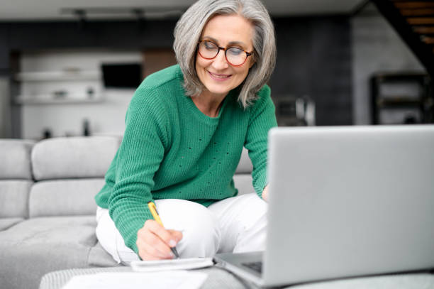 beautiful senior woman using laptop at home - retirement planning imagens e fotografias de stock