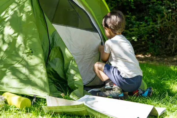 kid learning to pitch a tent on a summercamp. Vacation concept