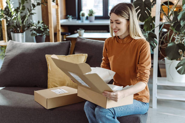 istock Smiling young woman opening a delivered package 1407164482
