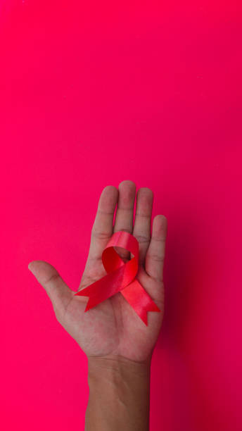 istock Hand holding a Red AIDS Ribbon with copy space for text isolated on red background 1407165852