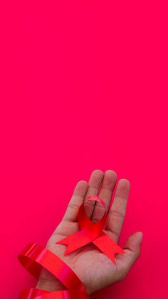 istock Hand holding a Red AIDS Ribbon with copy space for text isolated on red background 1407165881