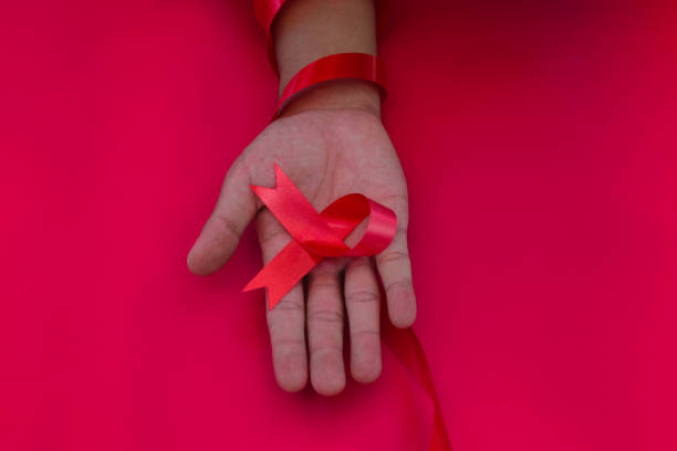 istock Hand holding a Red AIDS Ribbon with copy space for text isolated on red background 1407166132