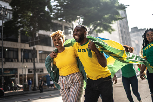 Amigos fanáticos brasileños caminando y celebrando al aire libre photo