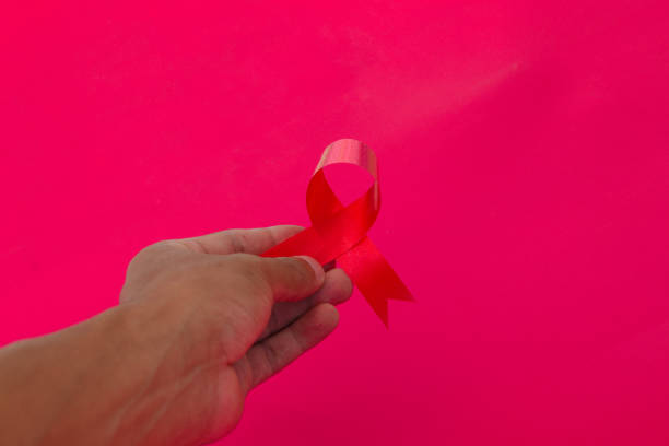 istock Hand holding a Red AIDS Ribbon with copy space for text isolated on red background 1407166222