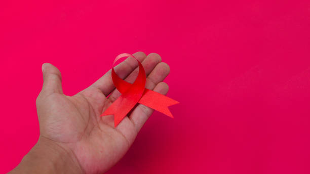 istock Hand holding a Red AIDS Ribbon with copy space for text isolated on red background 1407166316