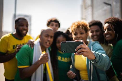 Brazilian fans watching soccer game using mobile phone outdoors