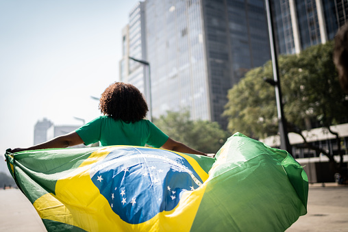 Aficionado brasileño caminando y sosteniendo una bandera brasileña en la ciudad photo