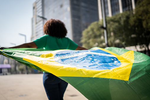 Brazilian fan walking and holding a brazilian flag on the city