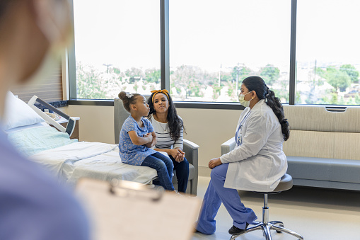 The young patient sits with her mother and talks to the pediatric surgeon.