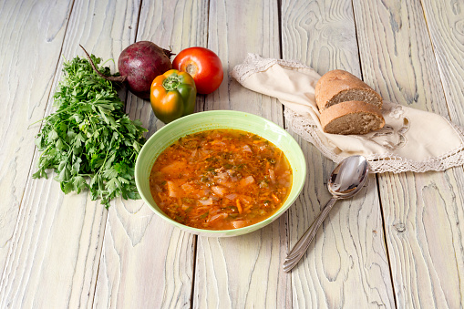 Borscht in a bowl and vegetables on a wooden background close-up (Ukrainian cuisine)