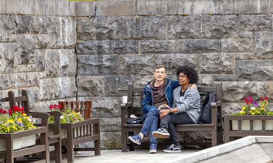 Dublin, Ireland - June 3, 2022: Gay couple sitting on the bench in the Garden of Remembrance in Dublin, Ireland