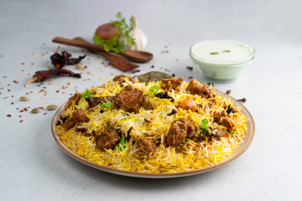 Indian spicy mutton Biryani with raita and gulab jamun Served in a dish side view on grey background Indian spicy mutton Biryani with raita and gulab jamun Served in a dish side view on grey background chicken meat photos stock pictures, royalty-free photos & images