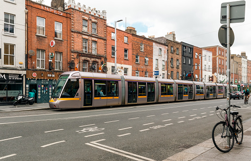 Tram along Princes Street in Edinburgh city center. People walking down the sidewalk. The Edinburgh trams went live in May 2014 and are operated by Transport for Edinburgh