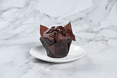 Double Chocolate Muffin Served in a dish side view on grey background