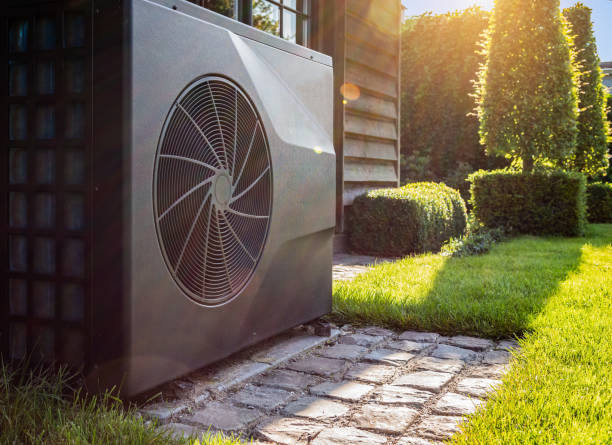 Air heat pump near pool house outdoors. Close-up of black full inverter heat pump outside in the garden, near wooden pool house on a sunny day. Lens flare on the image. energy efficient stock pictures, royalty-free photos & images