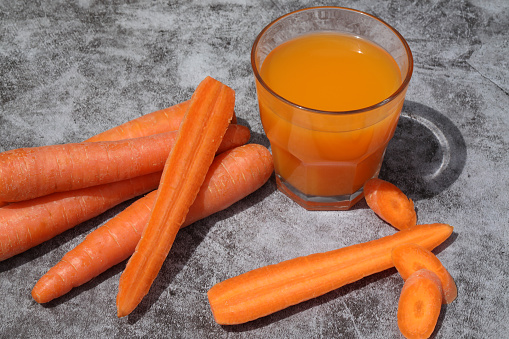 Glass of fresh carrot juice on the grey background and copy space