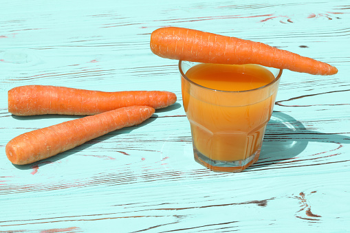 Glass of fresh carrot juice on the blue wooden background and copy space