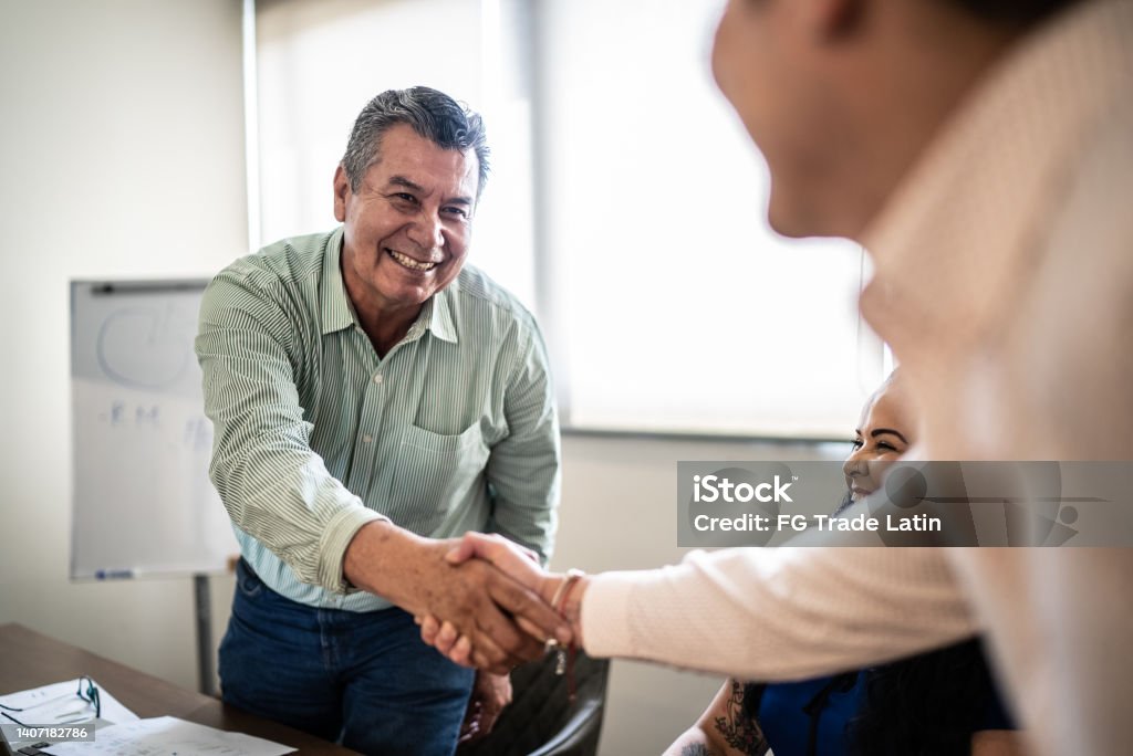Coworkers greeting and doing a handshake at work Agreement Stock Photo
