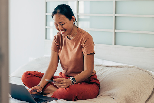 Asian woman using her credit card to pay for her online shopping.