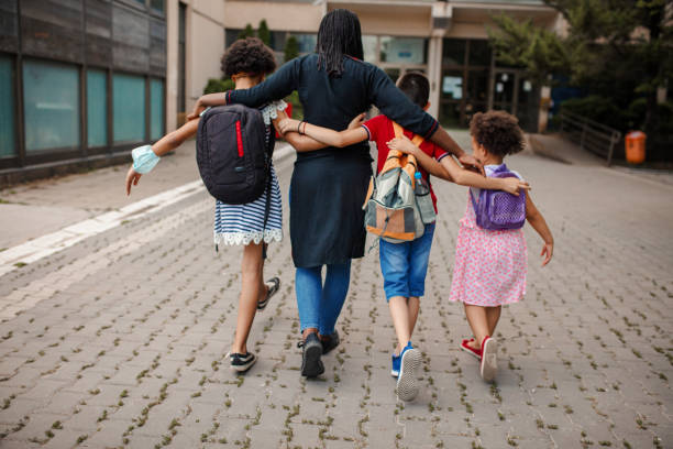 Black woman taking three kids to school