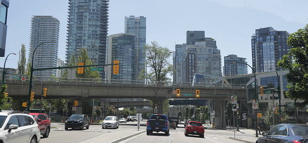 Vancouver, Canada - July 1, 2022: Traffic flows along Pacific Street under Granville Bridge. Background shows the upscale condominium towers of the Yaletown district in downtown. Summer morning.